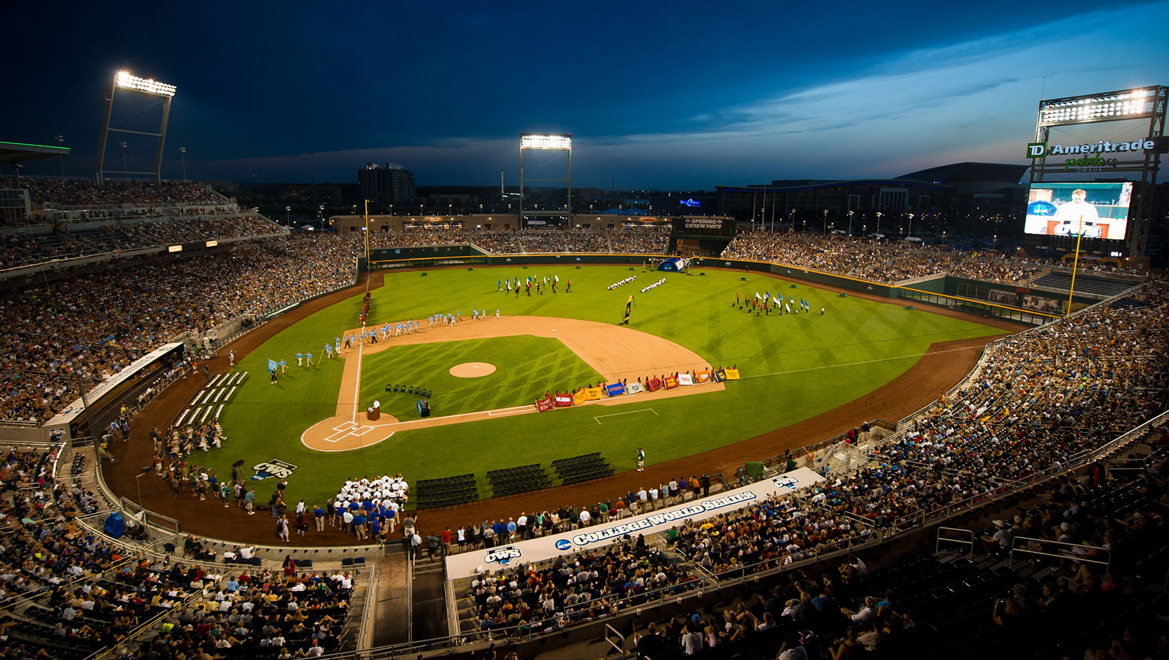 baseball stadium at dusk with teams on the field