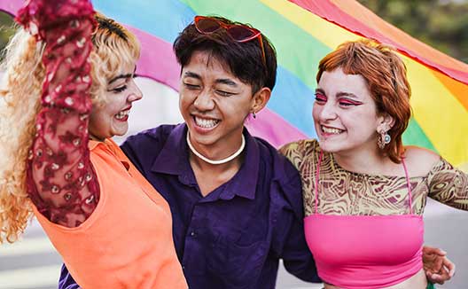 3 women celebrating in front of pride flag